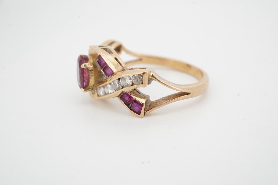 A ruby and diamond ring, of woven design, centring on an oval ruby, to a band set with calibré-cut rubies and brilliant-cut diamonds, mounted in gold, size N1/2, stamped 18K, gross weight 4 grams